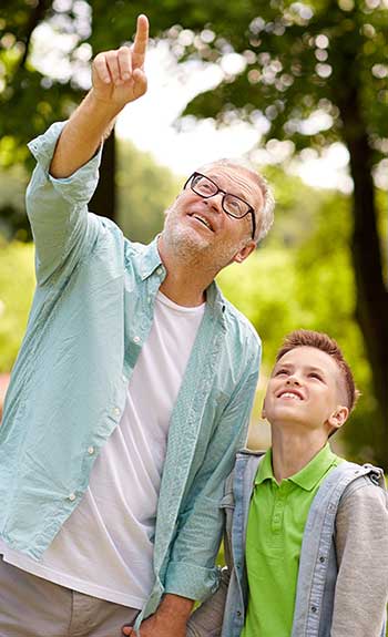image of grandfather and grandson in park looking up